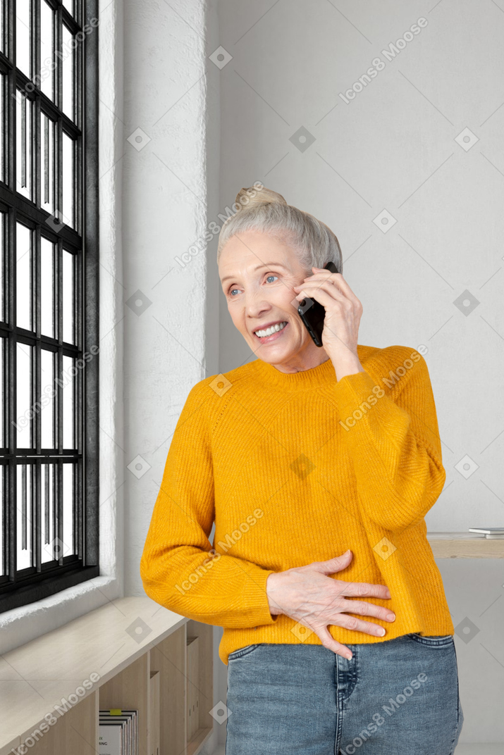 A woman in a yellow sweater talking on a cell phone