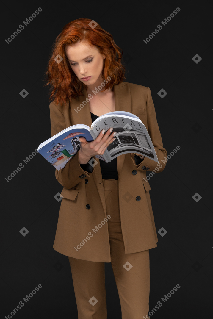 Vorderansicht einer jungen geschäftsfrau, die eine zeitschrift liest