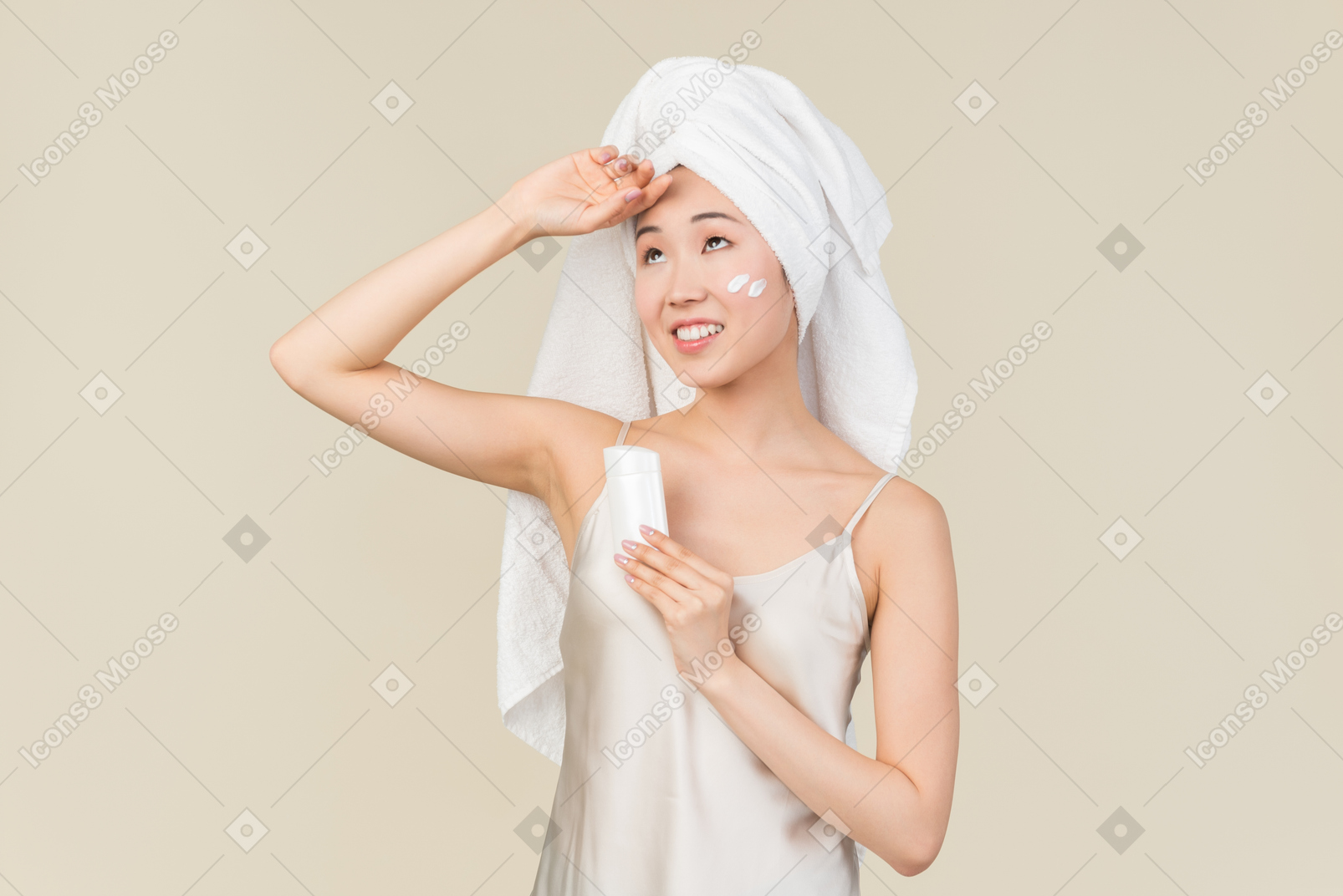 Dreamy asian woman in white towel holding cream bottle