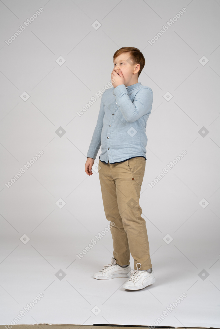 Niño con camisa azul de pie y bostezando