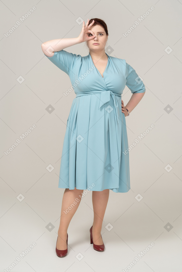 Vista frontal de uma mulher de vestido azul olhando por entre os dedos