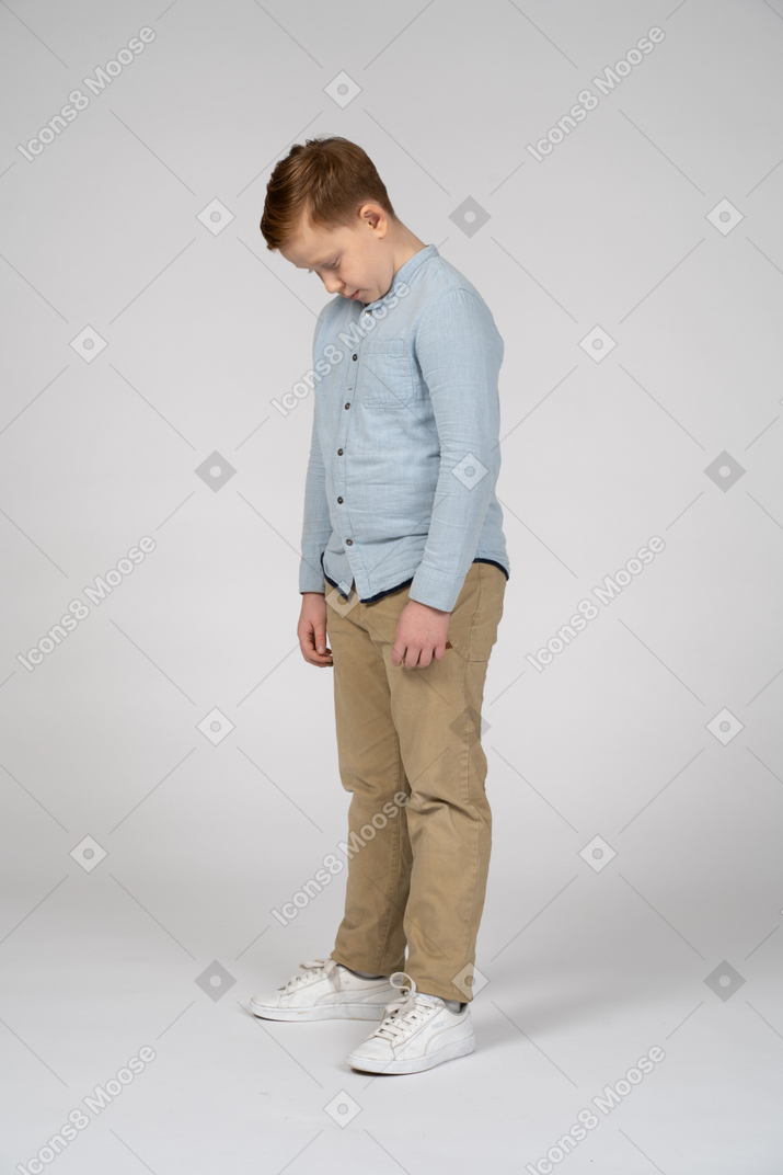 Cute boy standing with head bent down