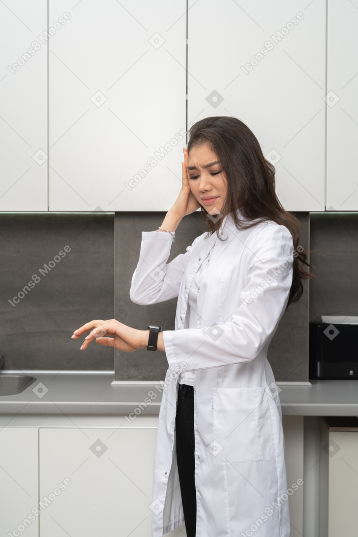 Close-up of an indignant  female doctor looking at her watch