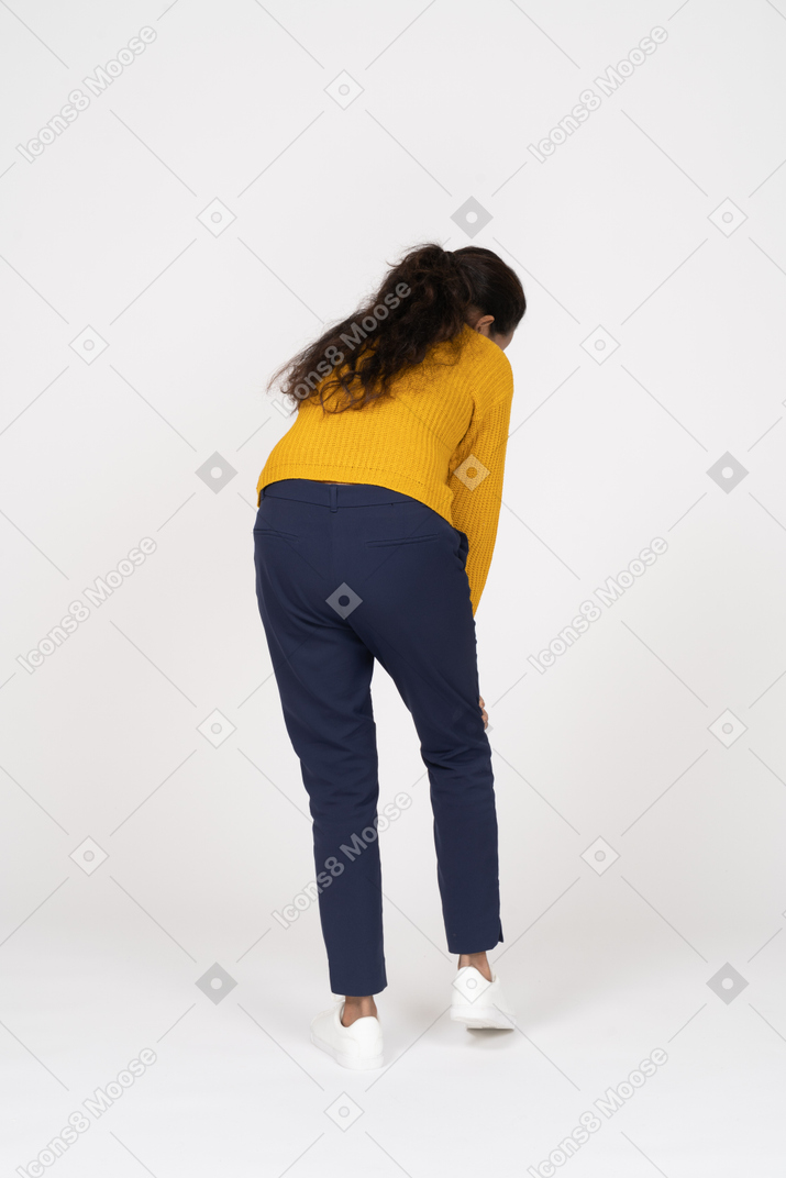 Vista posteriore di una ragazza in abiti casual che si china e si tocca il ginocchio dolorante