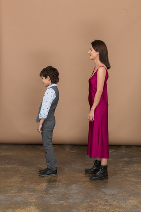 Femme en robe rouge et petit garçon debout de profil