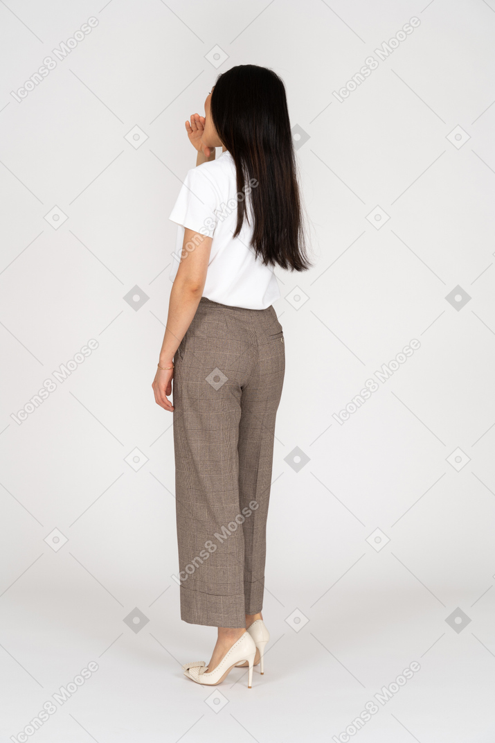 Three-quarter back view of a young woman in breeches biting her hand