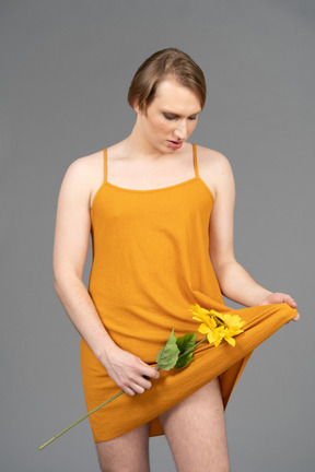 Junge nicht-binäre person, die sonnenblumen in ihrem kleid wiegt