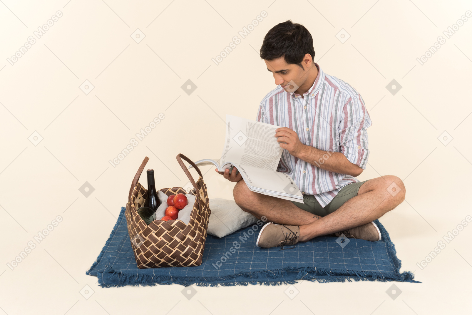 Young caucasian guy sitting on blanket and holding magazine opened