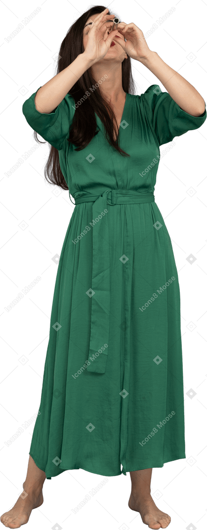 Vue de face d'une jeune femme en robe verte jouant de la flûte tout en levant les mains