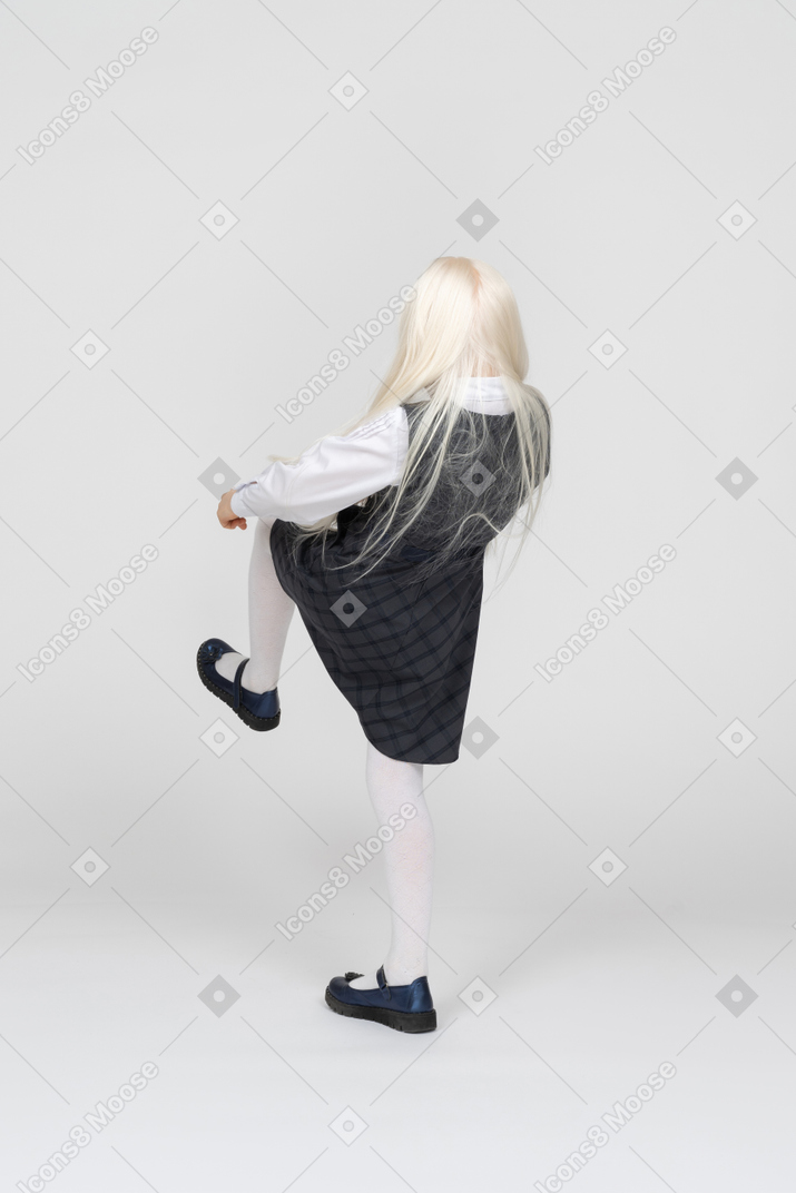 Back view of a schoolgirl kicking her feet