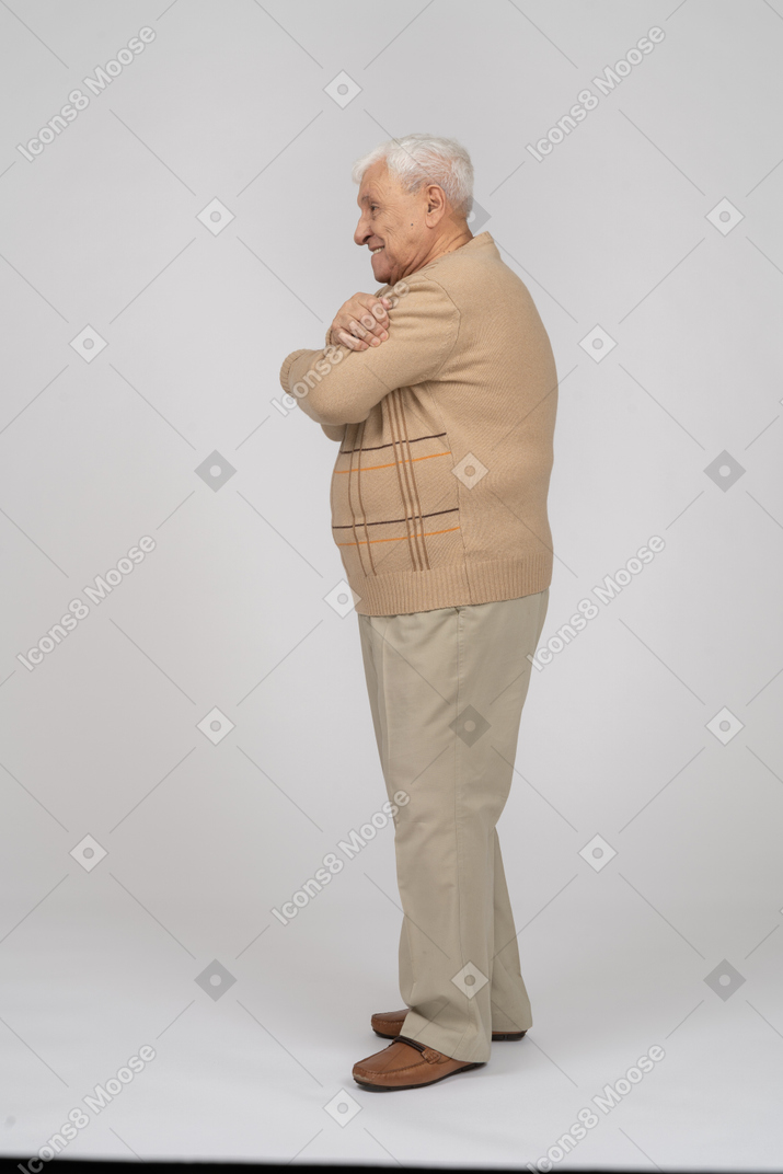 Vue latérale d'un vieil homme en vêtements décontractés se serrant dans ses bras