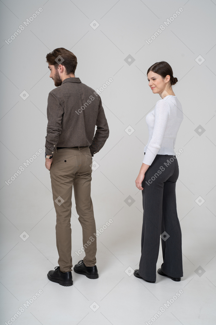Подозрительная молодая пара в офисной одежде, вид сзади в три четверти