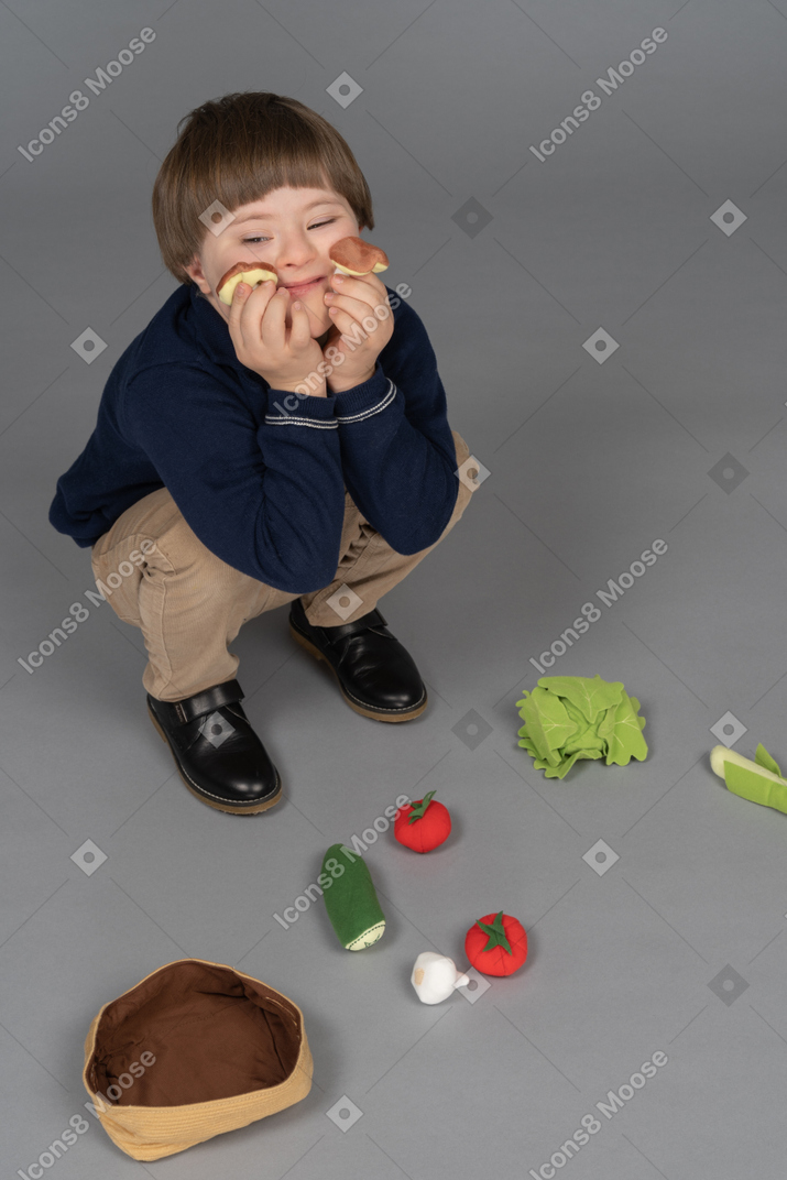 앉아있는 동안 플라스틱 장난감으로 그의 입을 닫는 어린 소년
