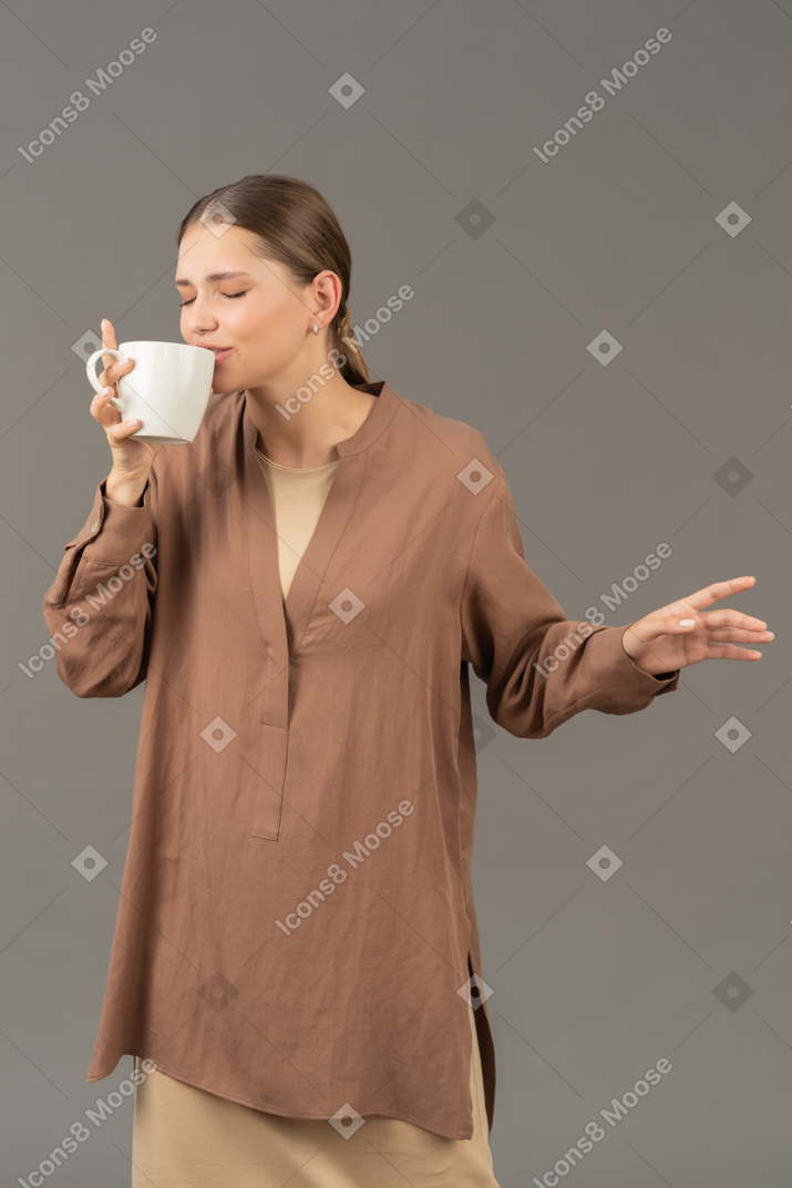커피 컵에서 한 모금을 마시는 젊은 여자