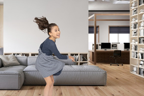 A young girl is jumping in a living room