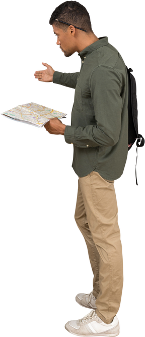 Side view of a man with a backpack holding a map and gesturing aside