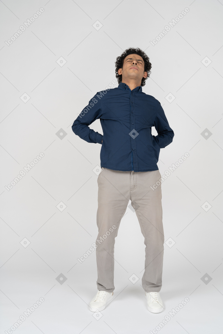 Front view of a man in casual clothes suffering from pain in lower back