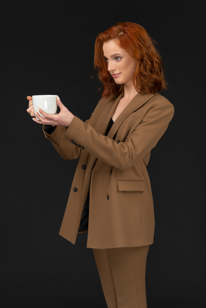 Foto de Una mujer con un traje negro y una camisa blanca con una taza de  café