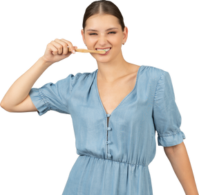 一个穿着蓝色连衣裙刷牙的年轻女子的前视图