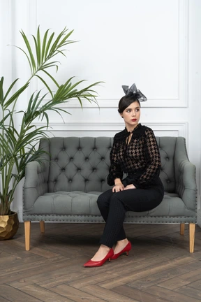 Woman in blouse sitting on couch in a room