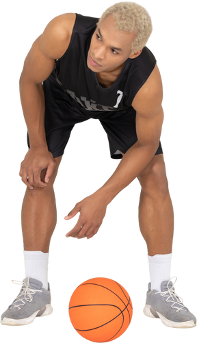 Front view of a young male basketball player standing by the ball