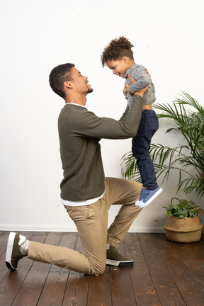 Young man on knees holding a boy in his arms