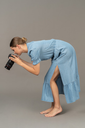 Side view of a young woman in blue dress taking shot