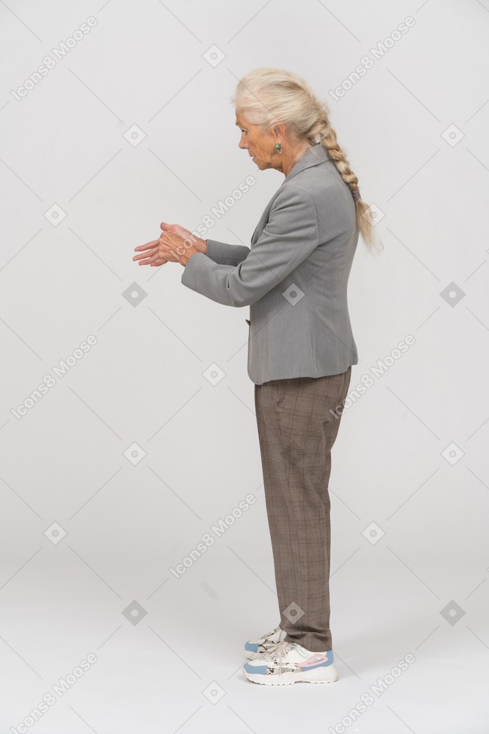 Side view of an old lady in suit showing something