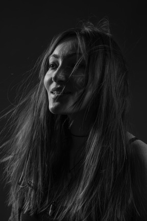 Noir three-quarter portrait of a young smiling female with ethnic facial art and messy hair