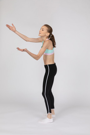 Side view of a teen girl in sportswear squatting and putting hands on hips