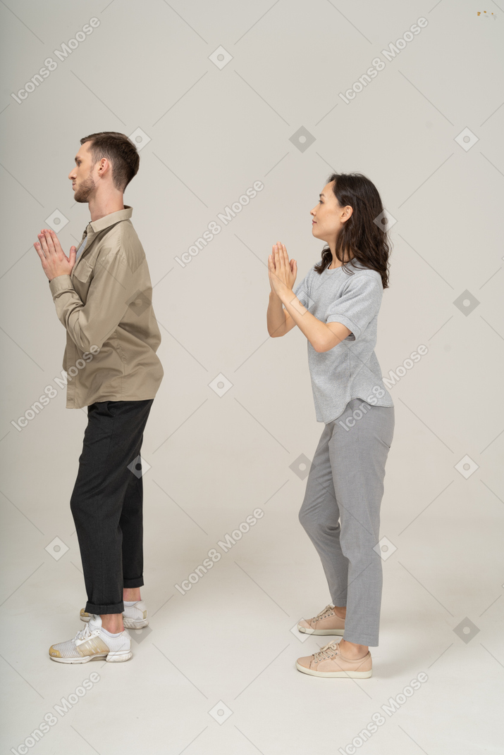 Vista laterale dell'uomo e della donna con le mani in preghiera