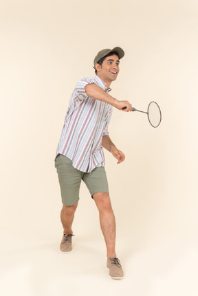 Laughing young caucasian guy holding racket