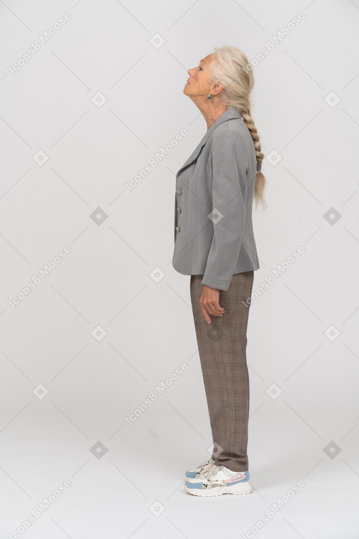 Vista lateral de una anciana en traje mirando hacia arriba