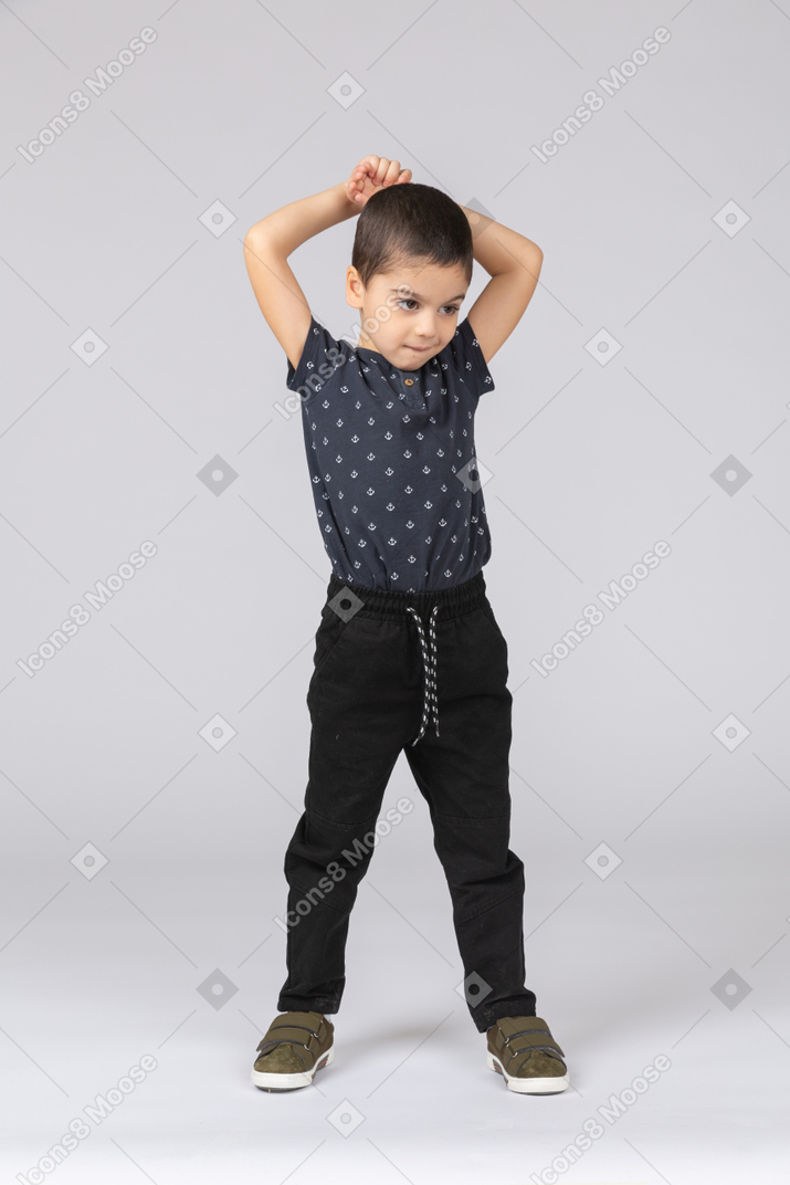 Front view of a cute boy standing with hands above head
