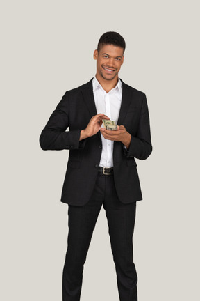 Front view of a young man in black suit wasting money