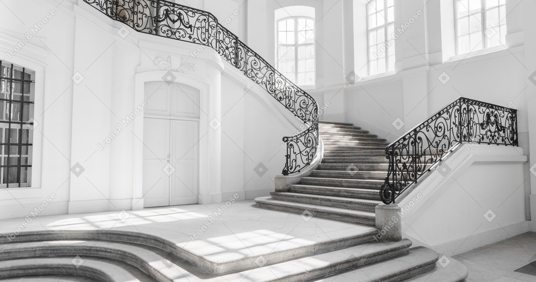 A beautiful empty hall with an openwork staircase and big white windows