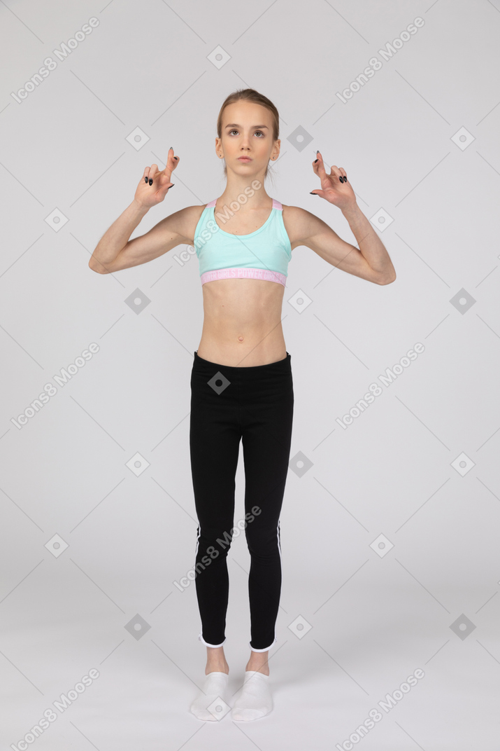 一个十几岁的女孩在运动服交叉手指的前视图