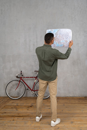Three-quarter back view of a man examining a map