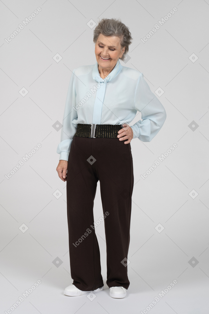 Front view of an old woman smiling with a hand on a hip