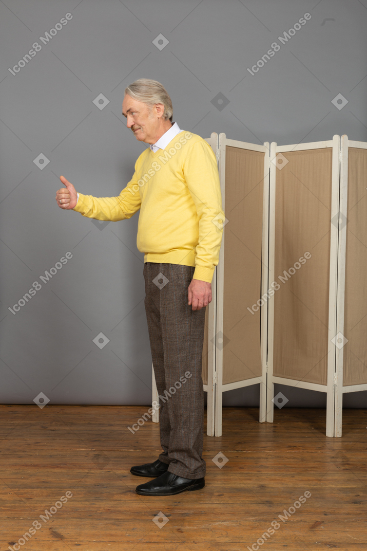 Vista laterale di un uomo anziano che mostra il pollice in su
