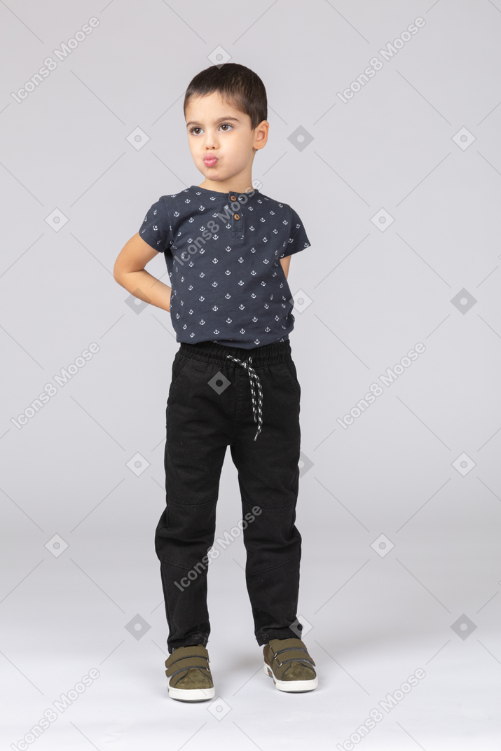 Front view of a cute boy posing with hands on back and making faces
