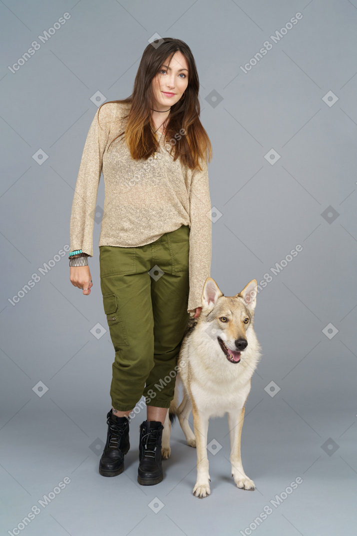 Pleine longueur d'un maître féminin debout près de son chien et regardant de côté