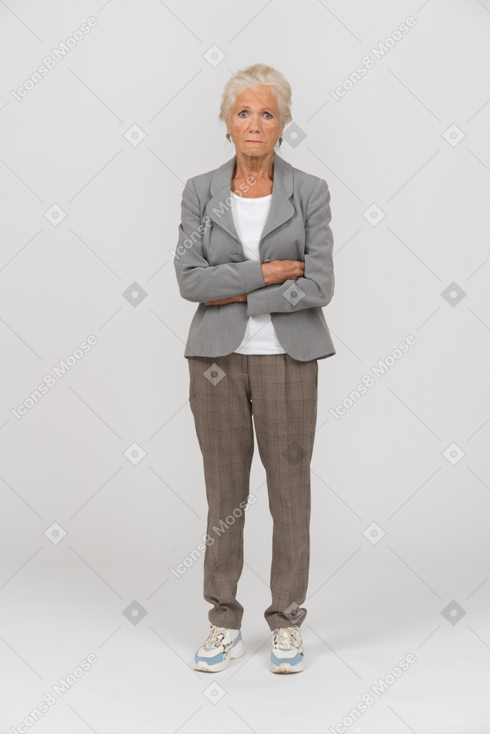 Front view of an old woman in suit posing with crossed arms