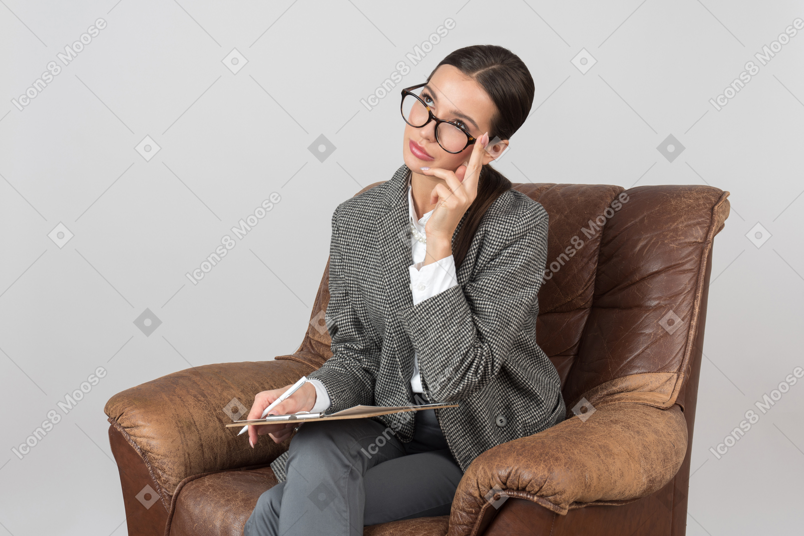 Pensive young woman sitting in chair and touching her eyeglasses