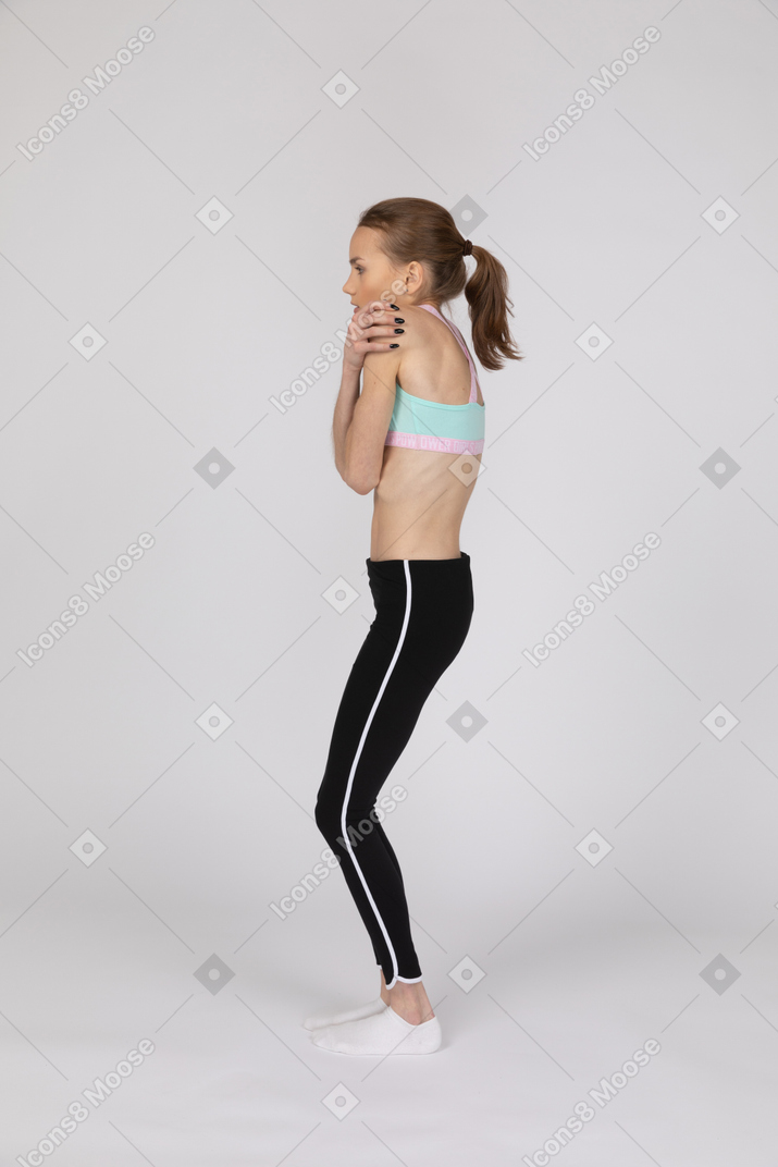 Vista lateral de uma adolescente tremendo em roupas esportivas