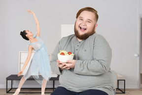 A man with a bowl of salad next to a woman dancing