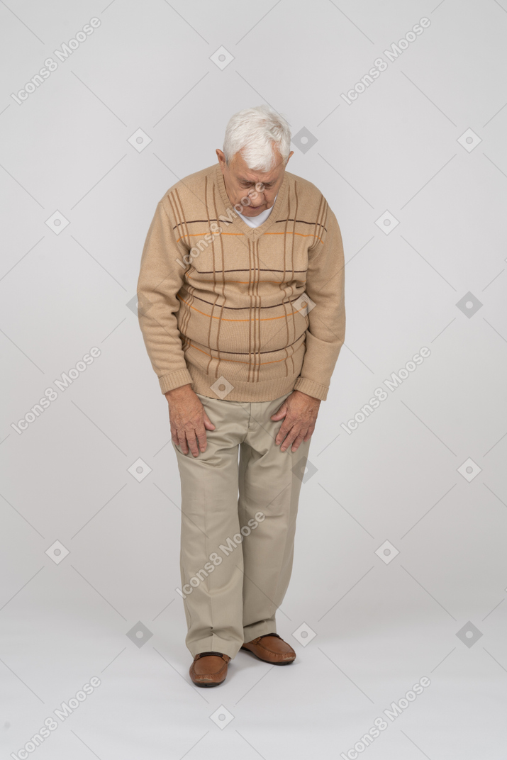 Front view of an old man in casual clothes looking down