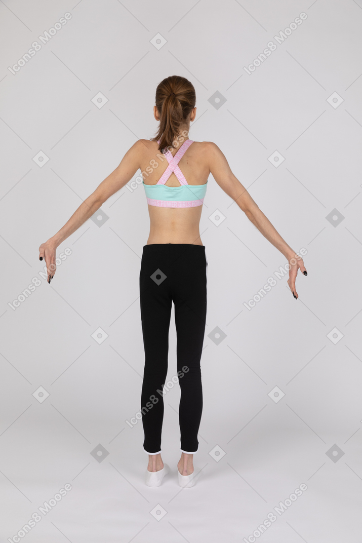 Vista traseira de uma adolescente em pé com os braços estendidos