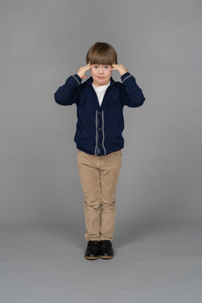 Portrait of a little boy touching his temples while looking stressed