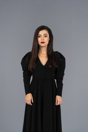 Front view of a young lady in a black dress standing still